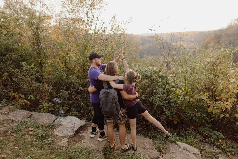 3名立博体育登录的学生在徒步旅行中俯瞰森林景观，拥抱和击掌